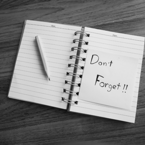 Notebook with a reminder note that says "Don't Forget," representing the importance of regularly reviewing and improving advertising campaigns rather than setting them and forgetting them.