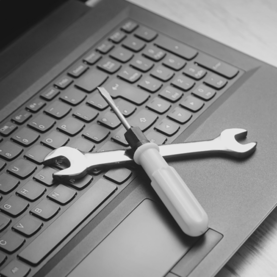 Tools resting on a laptop keyboard, representing website improvements, website maintenance, and fixing problems before investing in a complete website redesign.