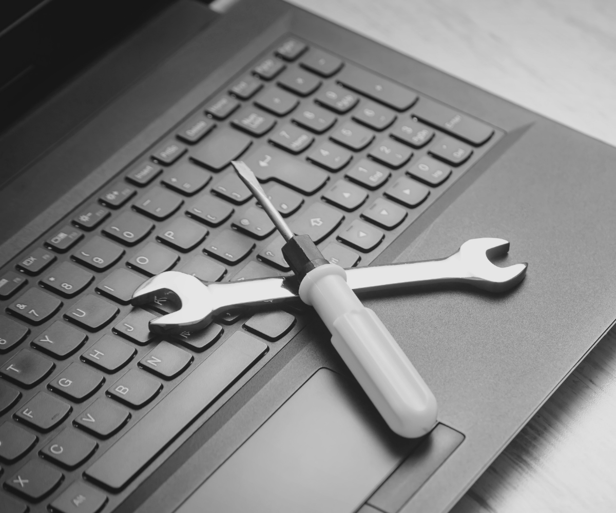 Tools resting on a laptop keyboard, representing website improvements, website maintenance, and fixing problems before investing in a complete website redesign.